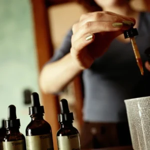 Person using a dropper bottle to add liquid to a cup.