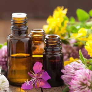 Amber glass bottles with essential oils surrounded by colorful flowers.