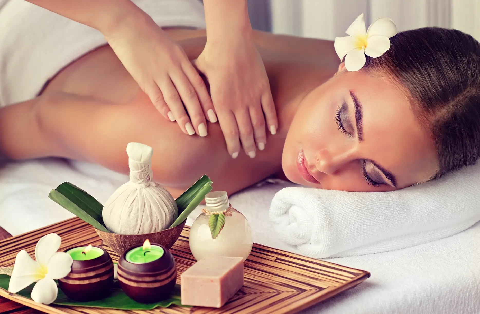 Woman enjoying a relaxing spa massage with aromatic candles nearby.
