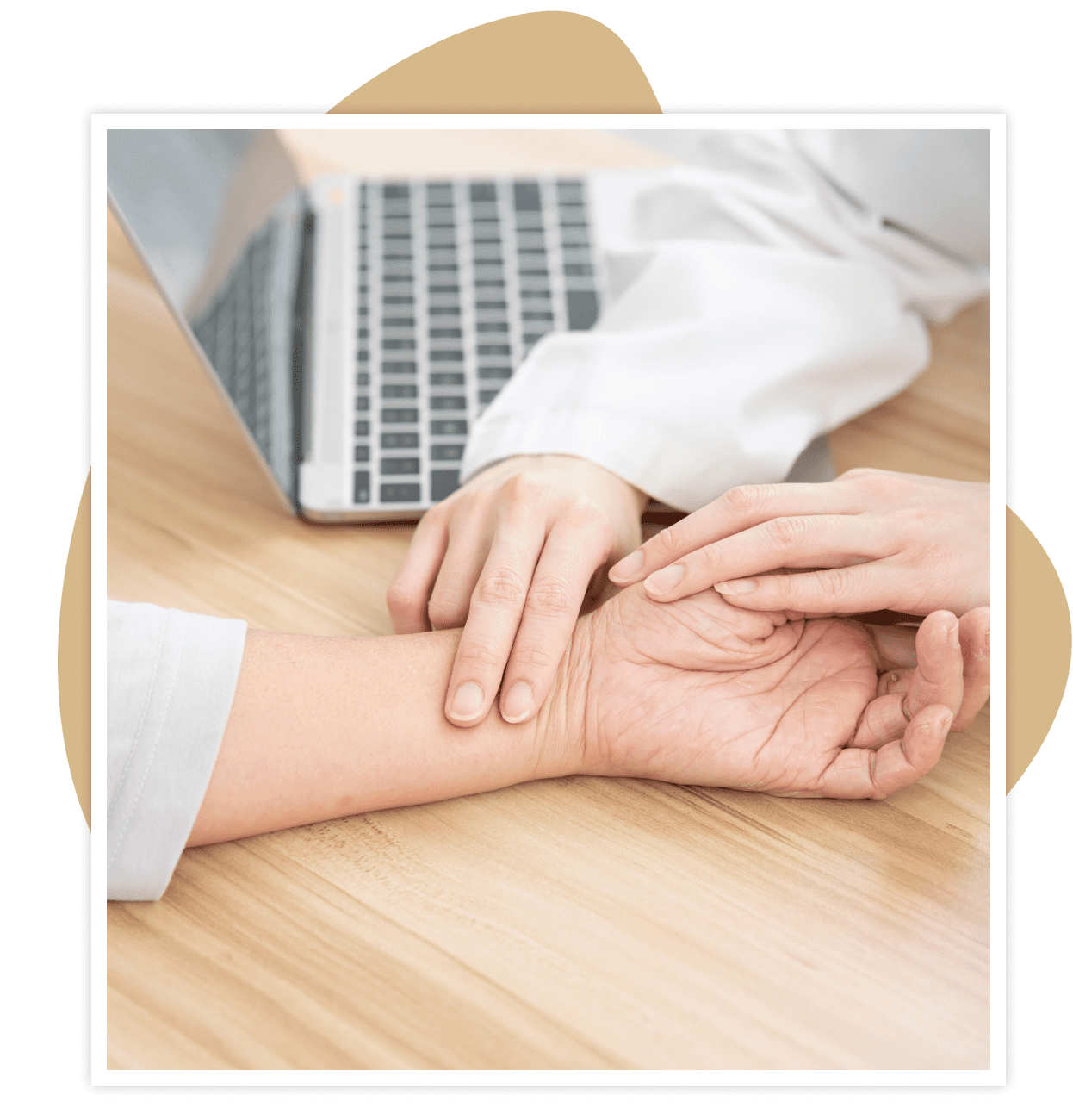 Doctor checking patient's wrist pulse with laptop in background.