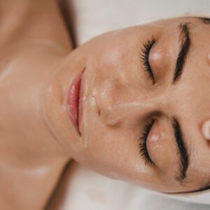 Close-up of a woman receiving a facial massage with cream applied.