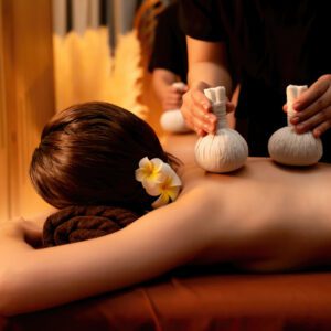 Person receiving a relaxing herbal massage with warm compresses.