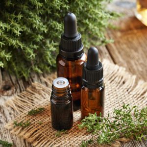 Three amber dropper bottles on a woven mat with greenery nearby.