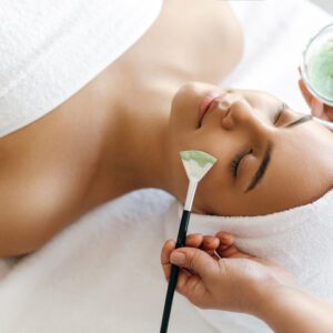 Woman receiving a facial treatment with a brush in a spa.