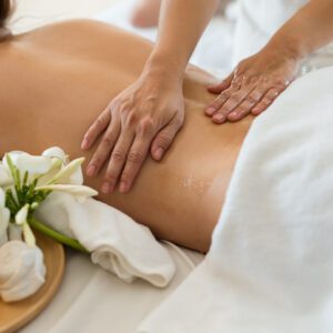 Person receiving a relaxing back massage with flowers nearby.