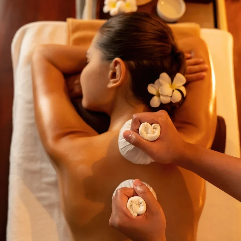 Woman receiving a relaxing hot stone massage with flower decorations.