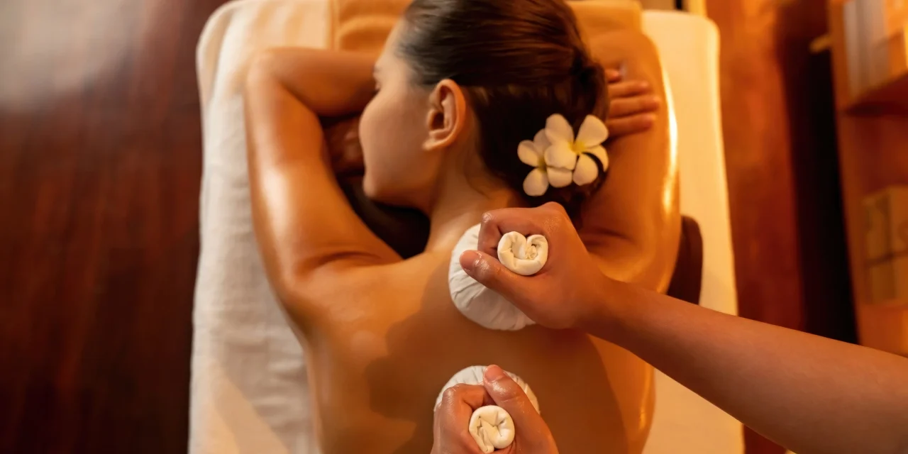 Woman receiving a relaxing hot stone massage with flower petals.