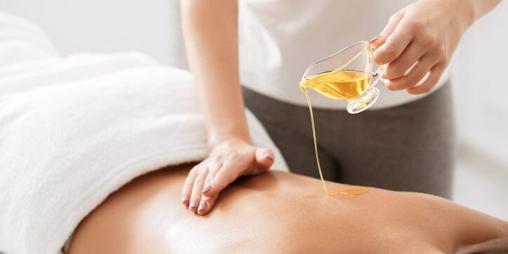 A person receiving an oil massage on their back in a spa setting.