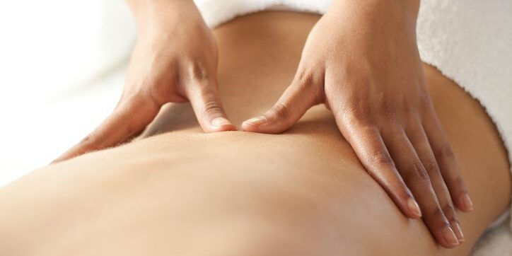 Hands performing a relaxing back massage on bare skin.