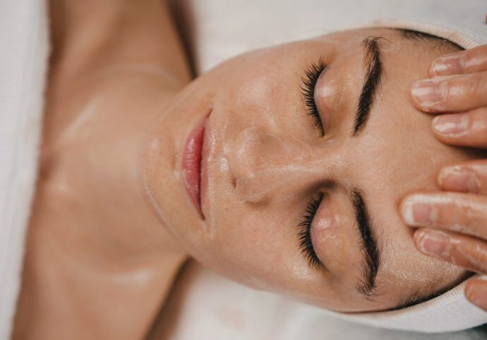 Close-up of a woman receiving a facial massage with cream applied.