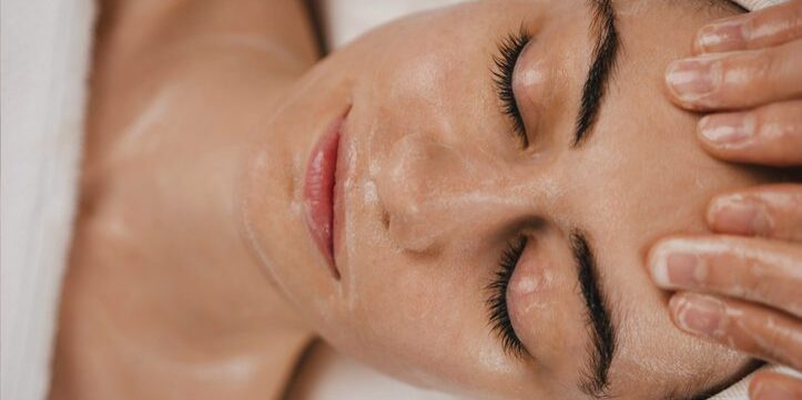 Close-up of a woman receiving a facial massage with cream applied.