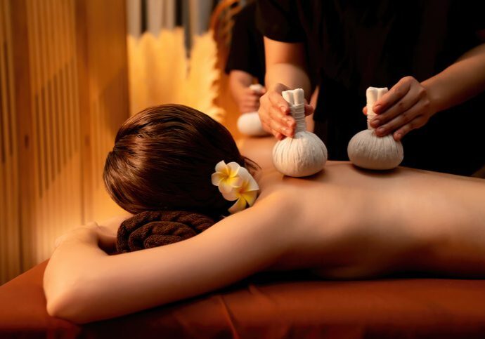 Person receiving a relaxing herbal massage with warm compresses.