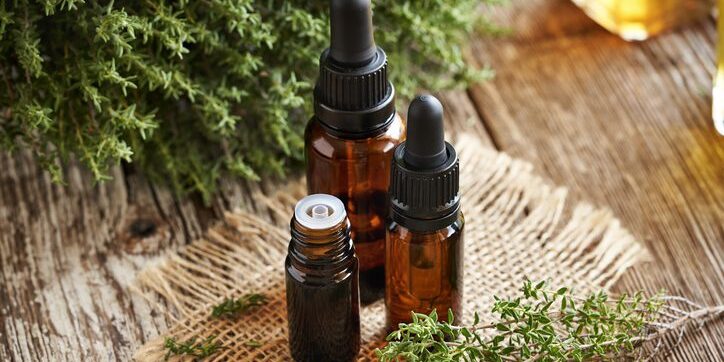 Three amber dropper bottles on a woven mat with greenery nearby.