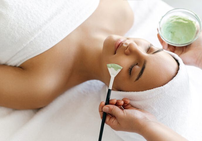Woman receiving a facial treatment with a brush in a spa.