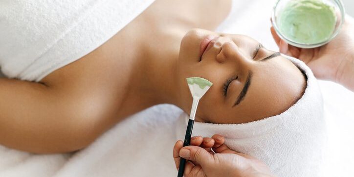 Woman receiving a facial treatment with a brush in a spa.