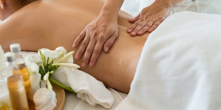 Person receiving a relaxing back massage with flowers nearby.