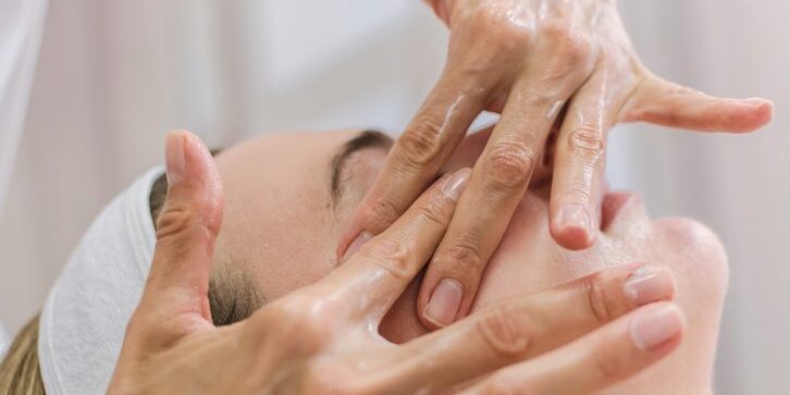 Therapist performing facial massage on a client.