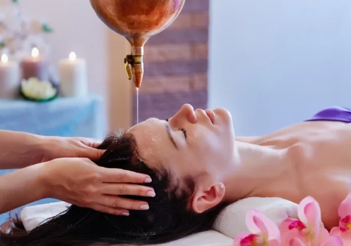 A woman receiving a calming head massage in a spa setting.
