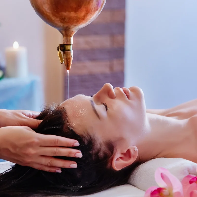 A woman receiving a calming head massage in a spa setting.