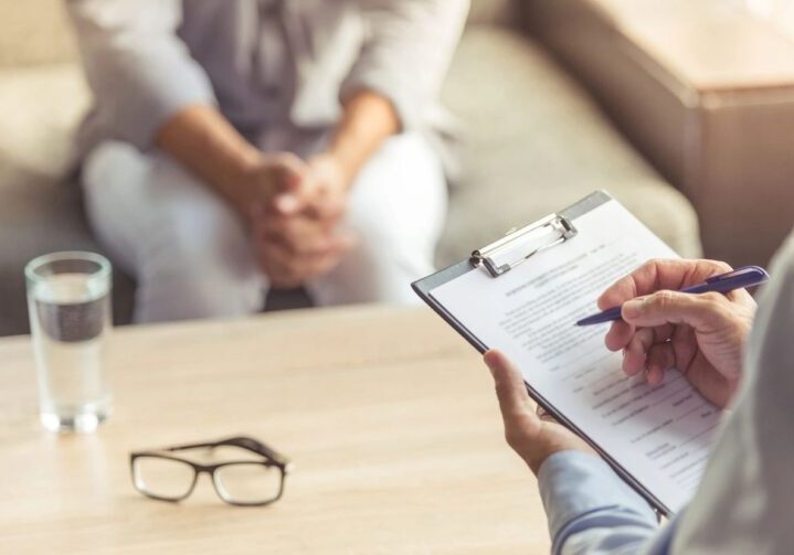Person consulting with a professional holding a clipboard and pen.
